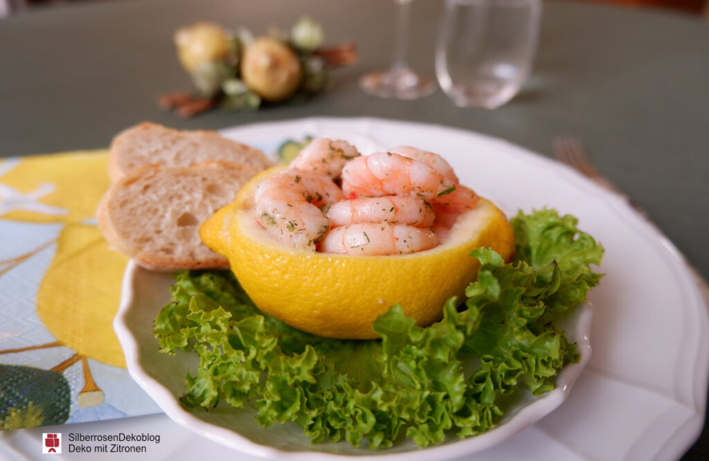Auf einem Teller als Vorspeise angerichtet Krabbensalat in einer ausgehöhlten Zitronenschale.