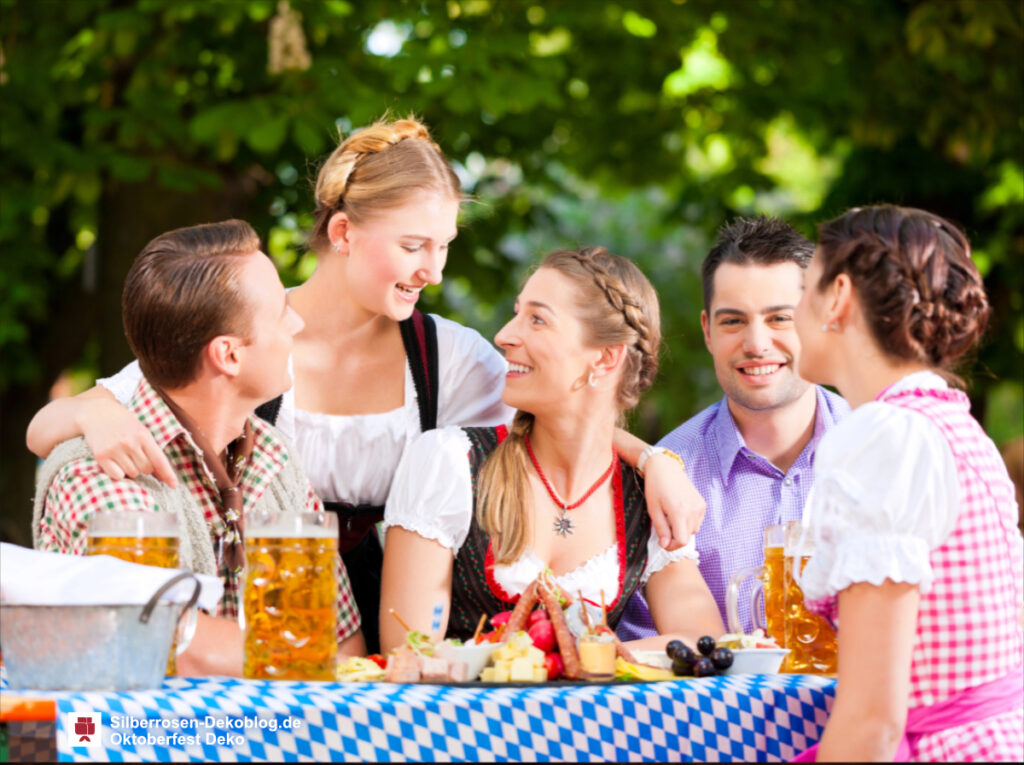 Fröhliche junge Menschen an einem Tisch mit Oktoberfest Deko im Garten.
