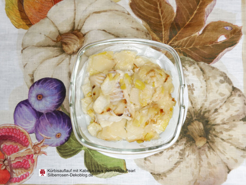 Auf einer Tischdecke mit Kürbisdesign steht eine kleine Auflaufform mit dem Kürbisauflauf mit Kabeljau.