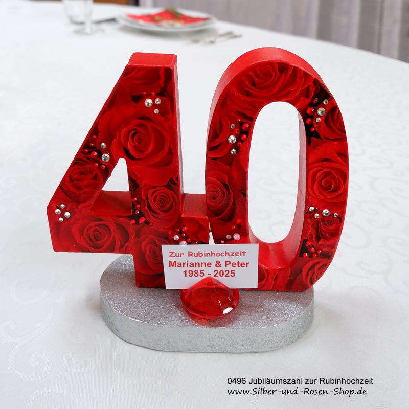 Jubiläumszahl zum Stellen, mit roten Rosenpapier und Glitzersteinen bezogen, auf silbern glitzerndem Sockel. Davor ein Acrylrubin, in dem eine kleine Karte mit den Namen und Daten des Jubelpaares steckt.