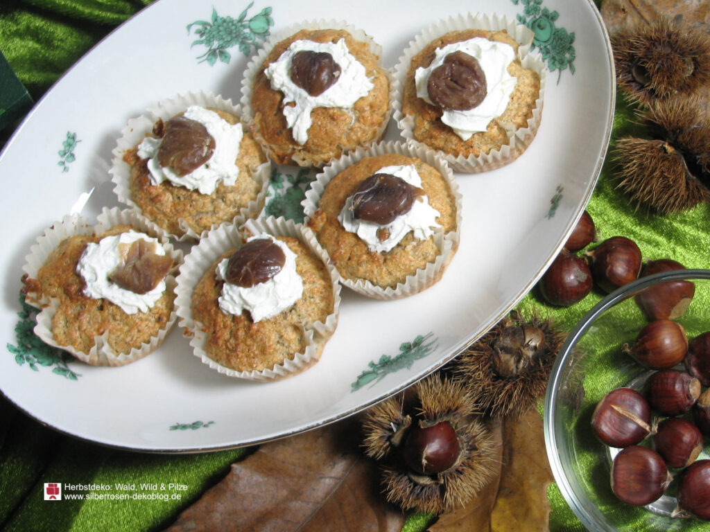Ansicht der Maronenmuffins, die aus Esskastanienmehl zubereitet werden. Darunter liegen Herbstblätter und Maroni.