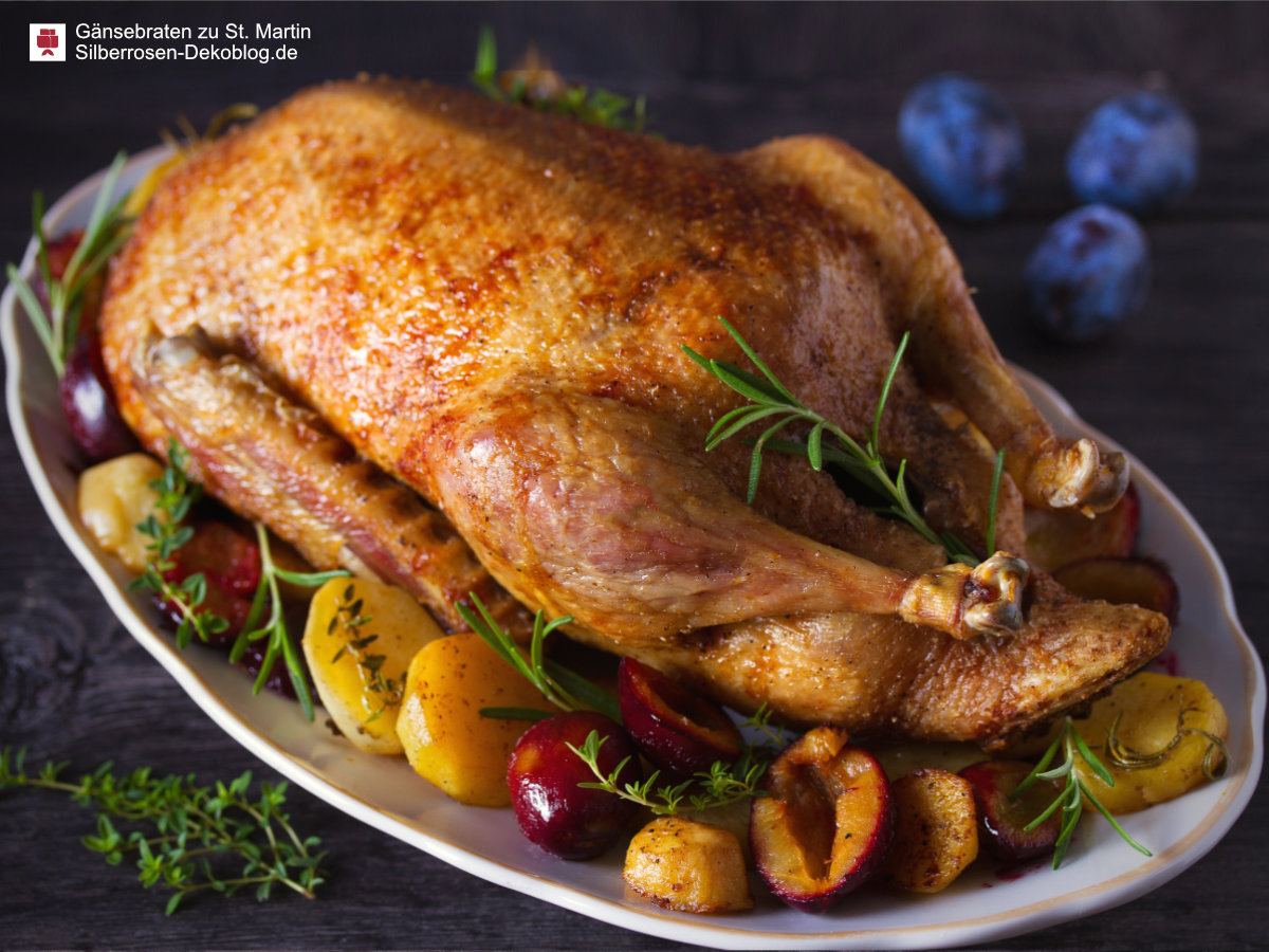Gebratene Gans auf einer Platte, umlegt mit geschmorten Kartoffeln und geschmorten Pflaumen, garniert mit Zweigen von Rosmarin und Thymian.