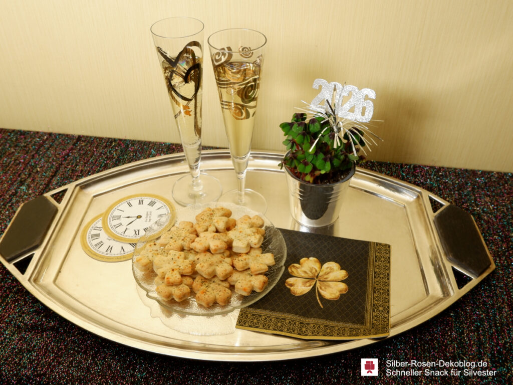 Silvestergedeck auf Tablett, Sektgläser, Untersetzer mit Uhrenmotiv, Serviette Golden Cloverleaf, Teller mit Käsegebäck und ein Glückskleetöpfchen.