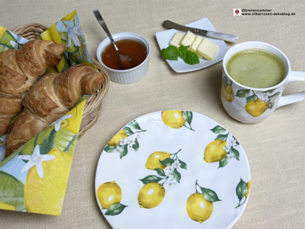 Gedeckter Platz mit Becher und Teller Maison Citron, Brotkorb, Honig, Butter und grünem Tee